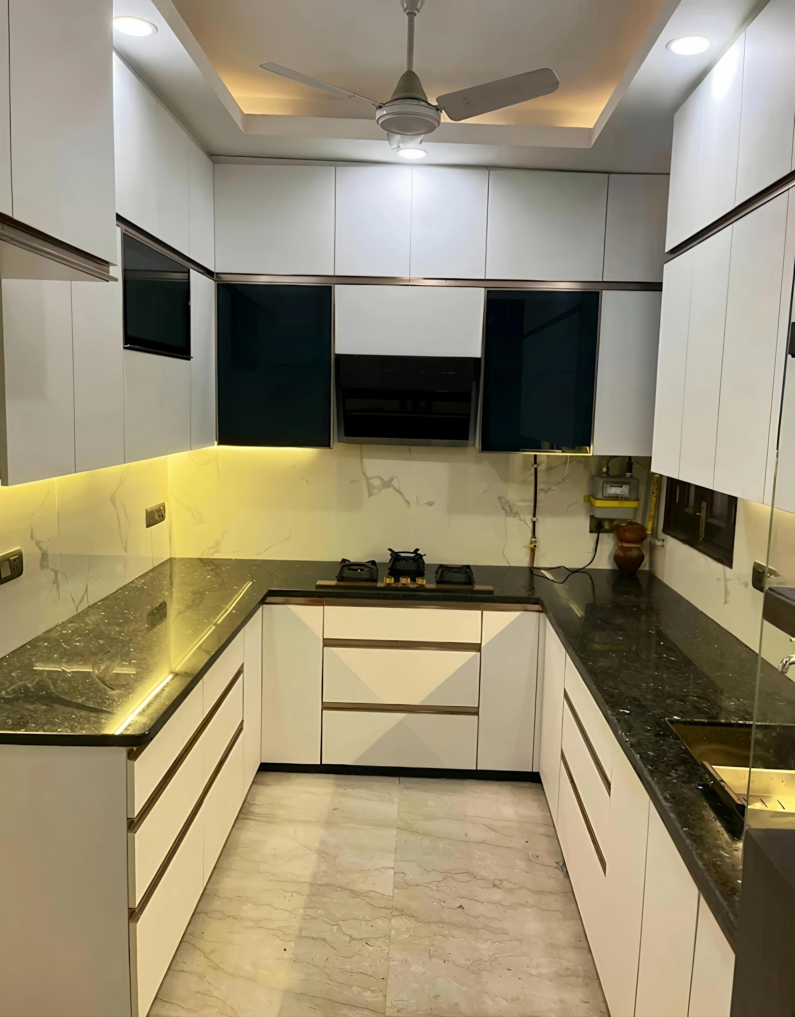 U-shaped kitchen with dark counters and warm profile lighting by STAR AVG ENTERPRISE