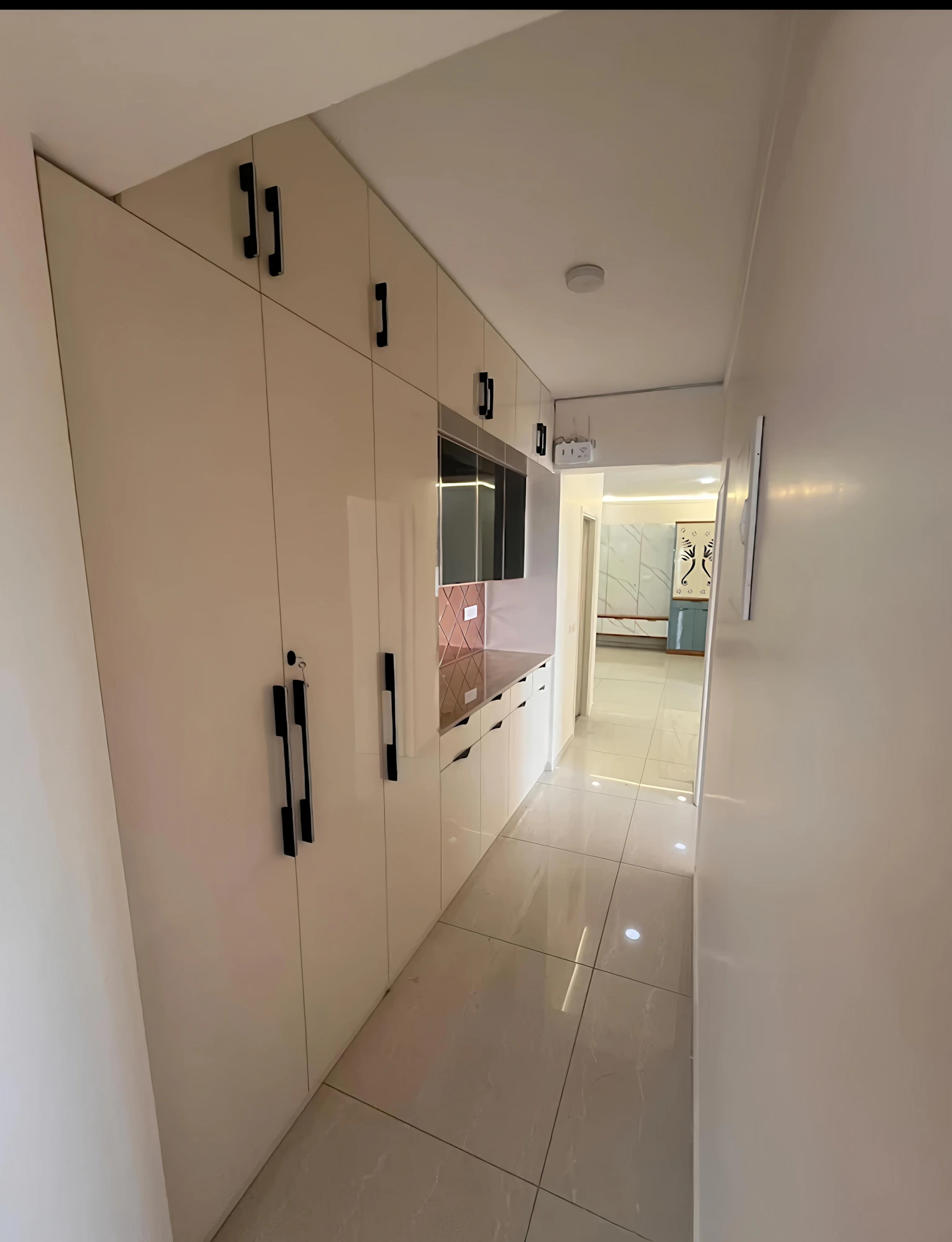 Full-length wardrobe run with TV niche along hallway